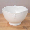 White ceramic bowl with a fleur-de-lis design on a wooden surface