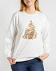 A woman wearing a white crewneck sweatshirt with a gold glittery Christmas tree graphic on the front, paired with blue jeans, against a light gray studio background.