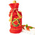 Red velvet wine bag with gold tassels and 'Tis the Season text, placed on a white surface with a decorative item.