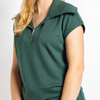 A woman wearing a dark green short-sleeve top with a half-zip collar, shown from the chest up against a plain light background.