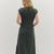 Lady standing in front of white background in green dress. 