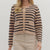 Woman wearing a striped cardigan and beige pants on a white background
